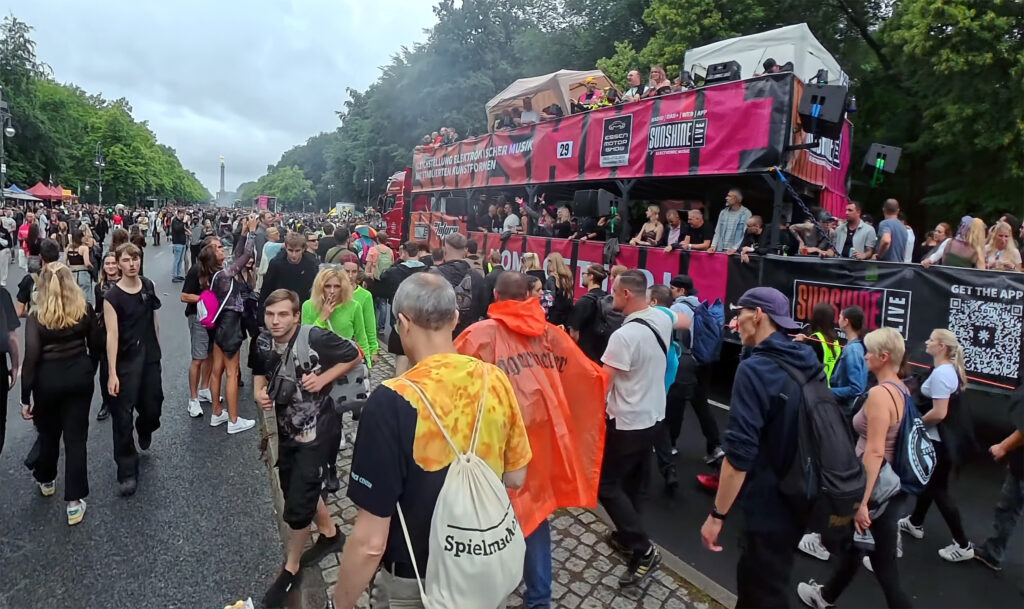 Ravers caminando junto a un camión de música rosa en la Straße des 17. Juni